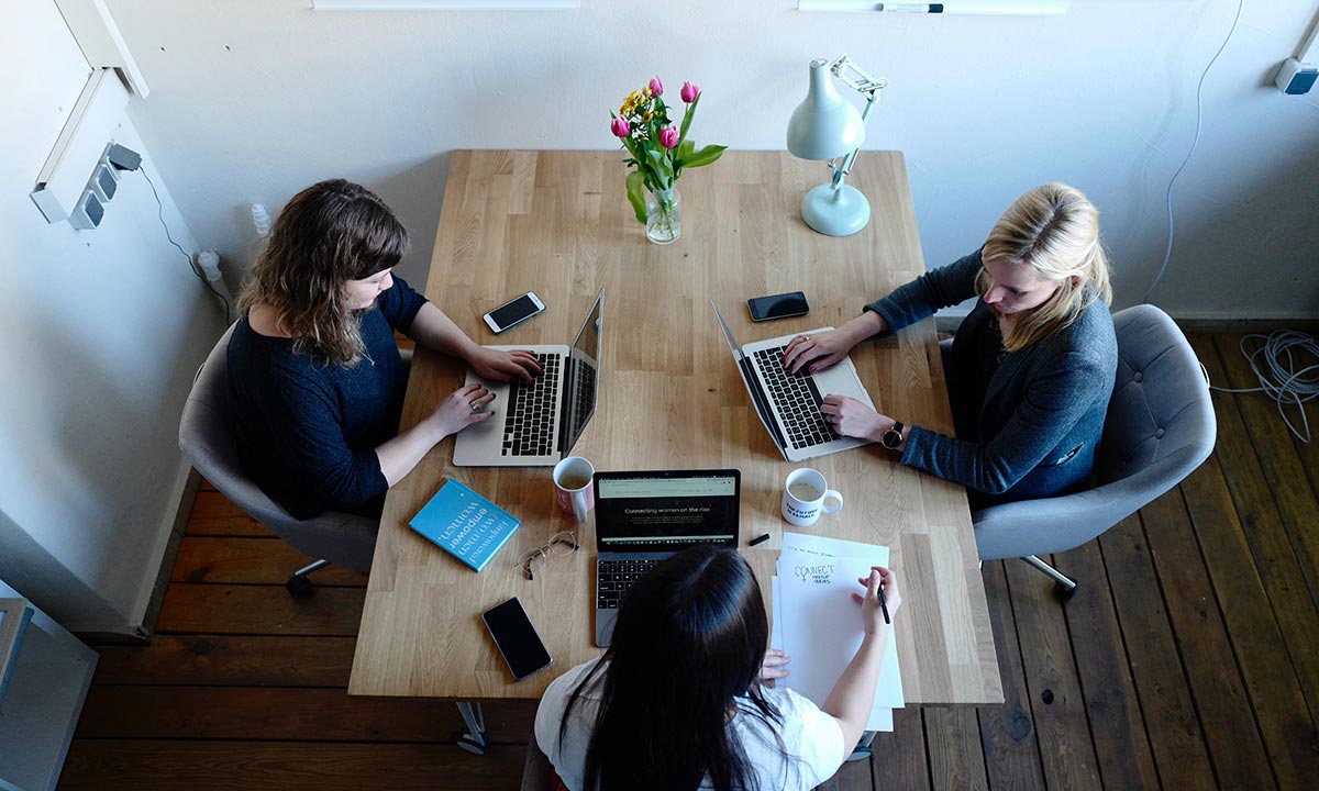 three coworkers collaborating together using unified communications on their apple laptop